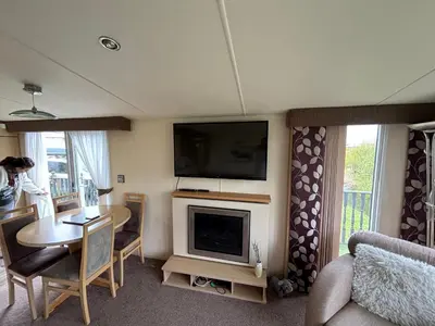 a living room with a table and a television and a living room with a table at The Beach Hideaway Pet Friendly 2 Bedroom Static Caravan Clarach Bay in Aberystwyth