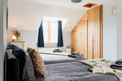 two beds in a bedroom with blue drapes at Cambrian Farm House by Birch Stays in Devils Bridge