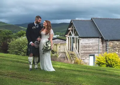 a bride and groom standing in front of a house at Cambrian Farm House by Birch Stays in Devils Bridge