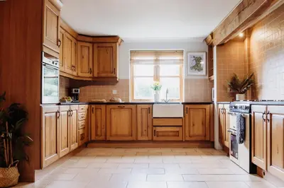 a kitchen with wooden cabinets and a window at Cambrian Farm House by Birch Stays in Devils Bridge