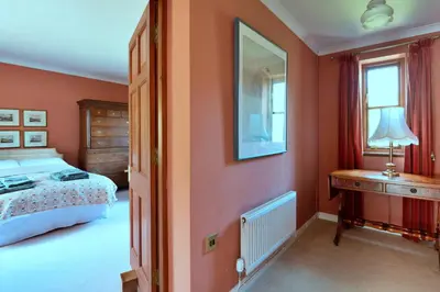 a bedroom with orange walls and a bed and a table at Finest Retreats - Cwmfron House in Llanidloes