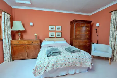 a bedroom with orange walls and a bed and a chair at Finest Retreats - Cwmfron House in Llanidloes