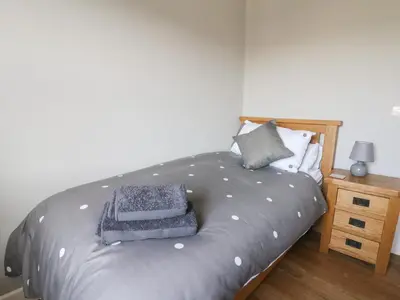 a bed with a gray comforter in a bedroom at Curtau in Builth Wells