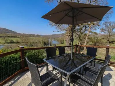 a table and chairs with an umbrella on a deck at Curtau in Builth Wells
