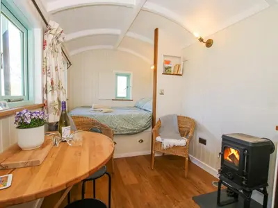 a room with a bed and a table with a wood stove at Gilberry Shepherds Hut in Church Stretton