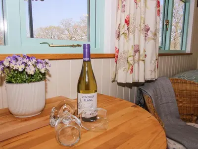 a bottle of wine sitting on a table with glasses at Gilberry Shepherds Hut in Church Stretton