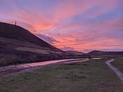 a sunset over a river with a hill at Duplex apartment with spectacular sea views! in Aberystwyth