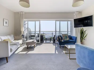 a living room with blue furniture and a large window at Verbier Luxurious Seaside Retreat in Aberdyfi