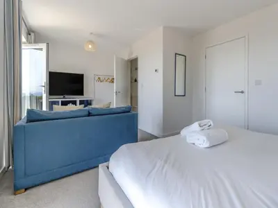 a bedroom with a blue couch and a television at Verbier Luxurious Seaside Retreat in Aberdyfi