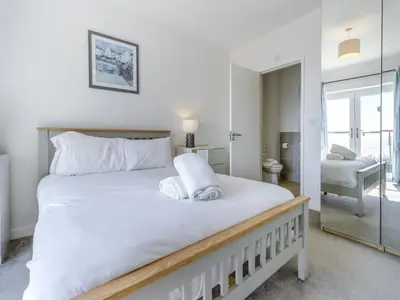 a bedroom with a large white bed with a mirror at Verbier Luxurious Seaside Retreat in Aberdyfi