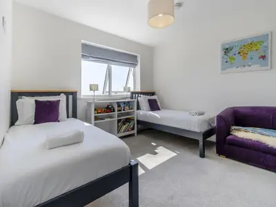 a bedroom with two beds and a purple couch at Verbier Luxurious Seaside Retreat in Aberdyfi