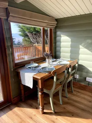 a dining room table with chairs and a window at Beautifully Restored Log Cabin in Trawsfynydd