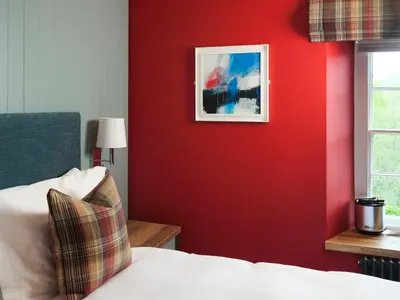 a bedroom with a red wall with a picture on the wall at The Bryntirion Inn in Llandderfel