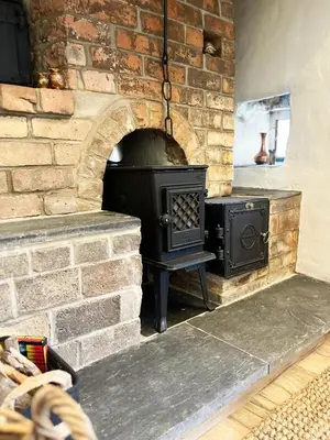 a brick fireplace with a stove in a room at Peaceful Dyfi Valley Cottage - Hendre-gau in Machynlleth