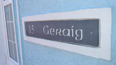 a sign on the side of a building that says is gardening at Geraig Aberaeron in Aberaeron