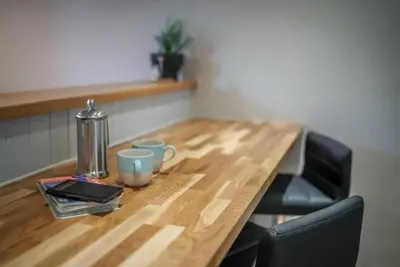 a wooden table with two mugs on top of it at Gegin-Faeldre in Llanbedr