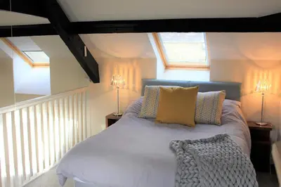a bedroom with a white bed with two windows at Coastal Bliss Charming Cottage near Borth beach in Borth