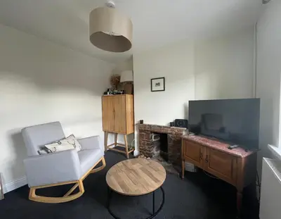 a living room with a chair and a table and a television at Cosy Cottage in Kington