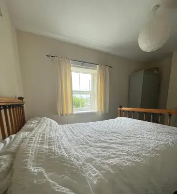 a bedroom with a white bed and a window at Cosy Cottage in Kington
