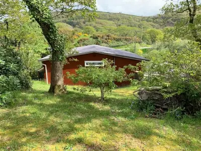 a red house in the middle of a field at Delightful Chalet Peaceful Site Near Aberdyfi in Tywyn