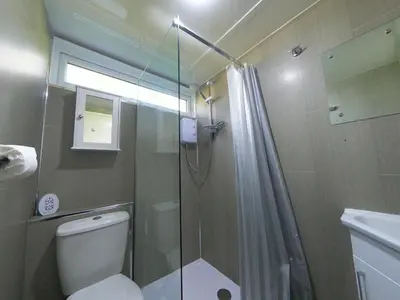 a bathroom with a shower and a toilet and a sink at Delightful Chalet Peaceful Site Near Aberdyfi in Tywyn