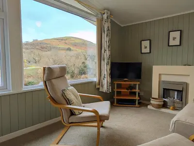 a living room with a chair and a large window at Delightful Chalet Peaceful Site Near Aberdyfi in Tywyn