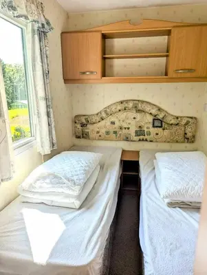 two twin beds in a room with a window at Family-Friendly Woodland Caravan Pool & Bar in Bryn-glâs Station
