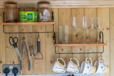 a wooden wall with wine glasses and utensils at Off-Grid Glamping - Quiet, Starry Escape in Yarpole
