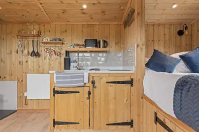 a kitchen and a bed in a room with wooden walls at Unplug & Reconnect, Romantic Retreat with Hot Tub in Yarpole