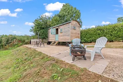 a tiny house with two chairs and a grill at Hot Tub Luxury Glamping - Private Stargazing Patio in Yarpole