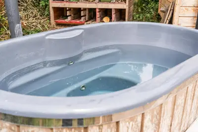 a jacuzzi tub in a wooden box with water at Hot Tub Luxury Glamping - Private Stargazing Patio in Yarpole