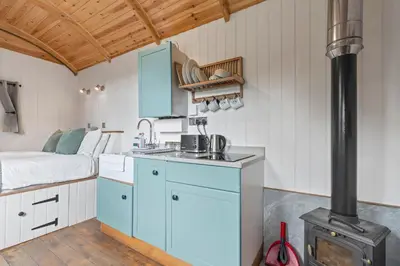 a kitchen with a stove and a bed in a room at Hot Tub Luxury Glamping - Private Stargazing Patio in Yarpole