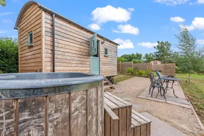 a wooden building with a hot tub and a table at Hot Tub Luxury Glamping - Private Stargazing Patio in Yarpole
