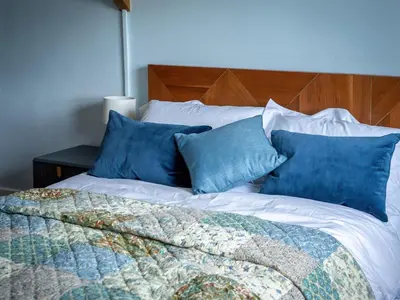 a bed with blue and white pillows on it at Coach House in Llanwrtyd Wells