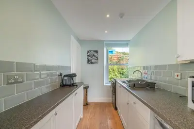 a kitchen with white counter tops and a window at Aberdyfi Sea View Apartment in Aberdyfi