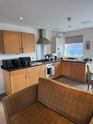 a kitchen with wooden cabinets and a couch at Modern, sleeps 6, rural market town, Llani in Llanidloes