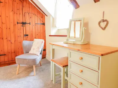 a bedroom with a dresser and a mirror and a chair at Ty Glan Yr Afon in Dolgellau