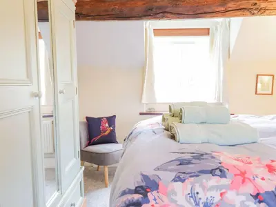 a bedroom with a bed and a window and a chair at Ty Glan Yr Afon in Dolgellau