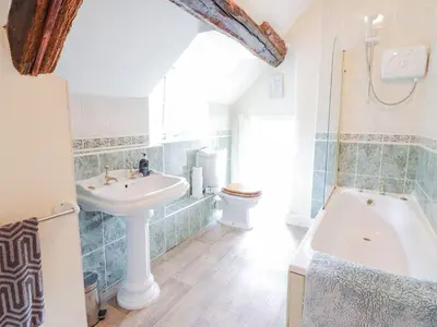 a bathroom with a sink and a toilet and a tub at Ty Glan Yr Afon in Dolgellau