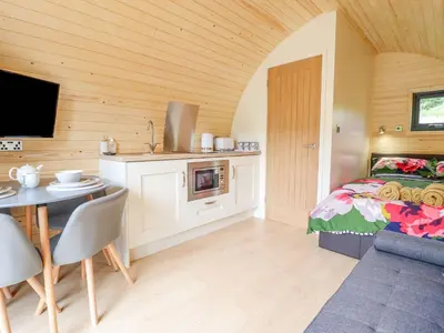 a bedroom with a bed and a table and a kitchen at Briallen in Dolgellau