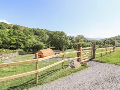 a wooden fence with a wooden boat in a field at Eirlys in Dolgellau