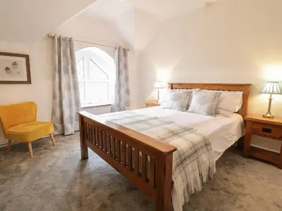 a bedroom with a bed and a chair and a window at Dwynant in Dolgellau