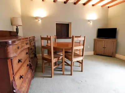 a dining room with a table and chairs and a television at Dwynant in Dolgellau