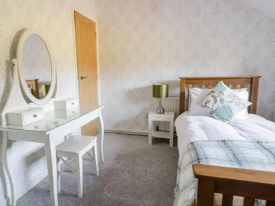 a bedroom with a bed with a dressing table and a mirror at Dwynant in Dolgellau