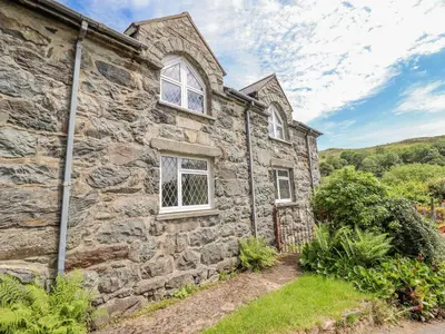 an old stone house with two windows and a yard at Dwynant in Dolgellau