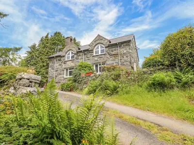 a stone house on a hill with a dirt road at Dwynant in Dolgellau