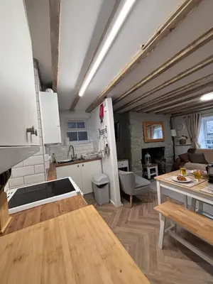 a kitchen with white cabinets and a wooden table at The Cottage on the Rock in Barmouth