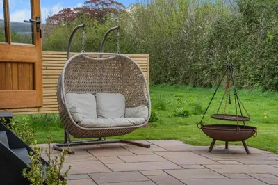 a wicker chair on a patio with a swing at 1 Bed in Brecon oc-t31948 in Bronllys