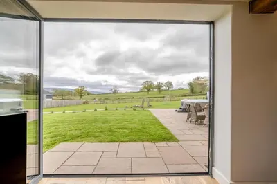 a sliding glass door leading to a patio with a table at 6 Bed in Llanwern oc-w31947 in Brecon