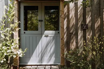 a door to a house with a fence at The Charcoal Hut woodland retreat in Llandovery
